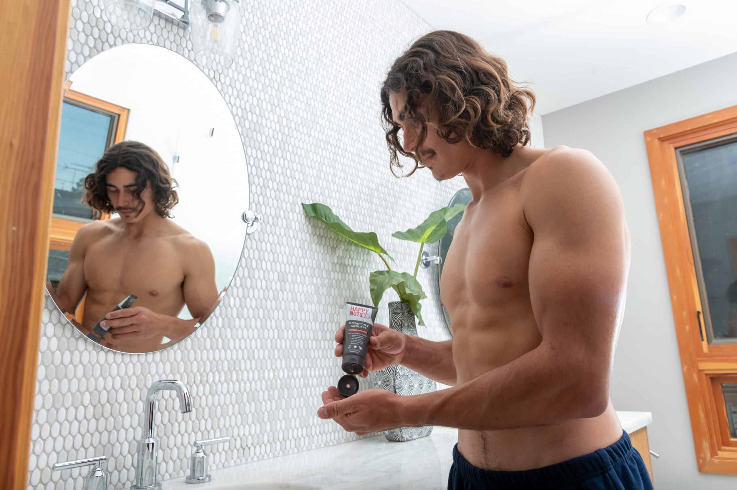 a man holding a tube of cream in front of a mirror